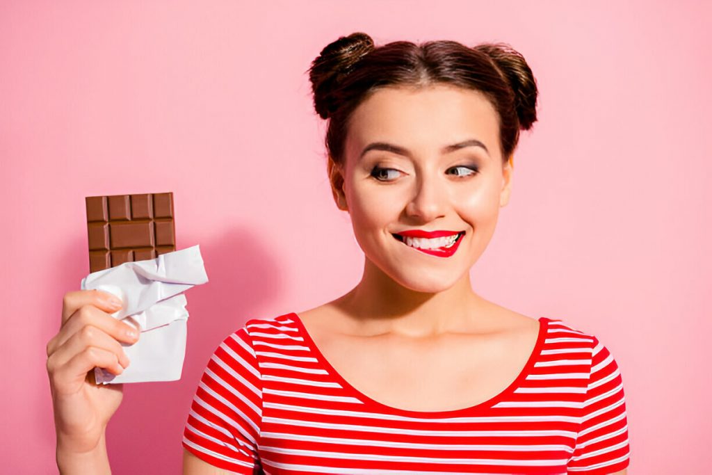 Mulher ansiosa segurando doce – fome emocional causada por hormônios