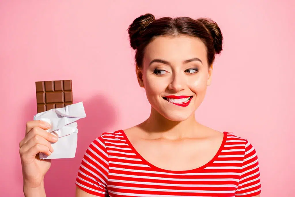 Mulher ansiosa segurando doce – fome emocional causada por hormônios